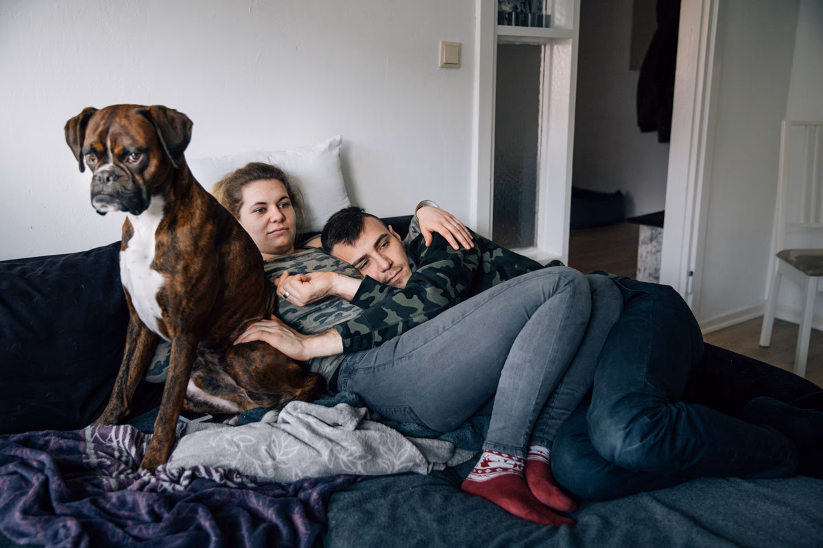 Airsoft-Spieler Len mit seiner Freundin Nina und dem Boxer Diego in seiner Wohnung in Hamburg. Seine Urgroßmutter wurde von den Nazis im Konzentrationslager Auschwitz-Birkenau ermordet. Er sagt, dass das »Spielen« mit Airsoft-Waffen für ihn nichts mit echtem Krieg zu tun habe.